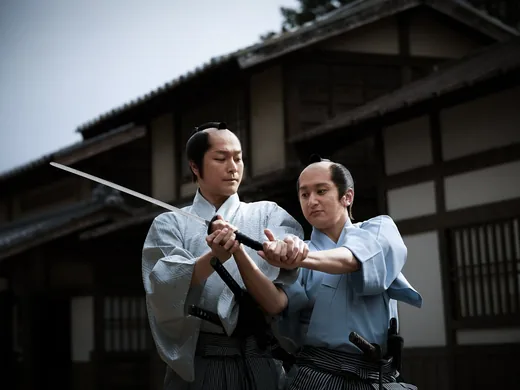 Gasse mit roten Gitterfassaden und Papierlaternen im Filmdorf Uzumasa in Kyoto