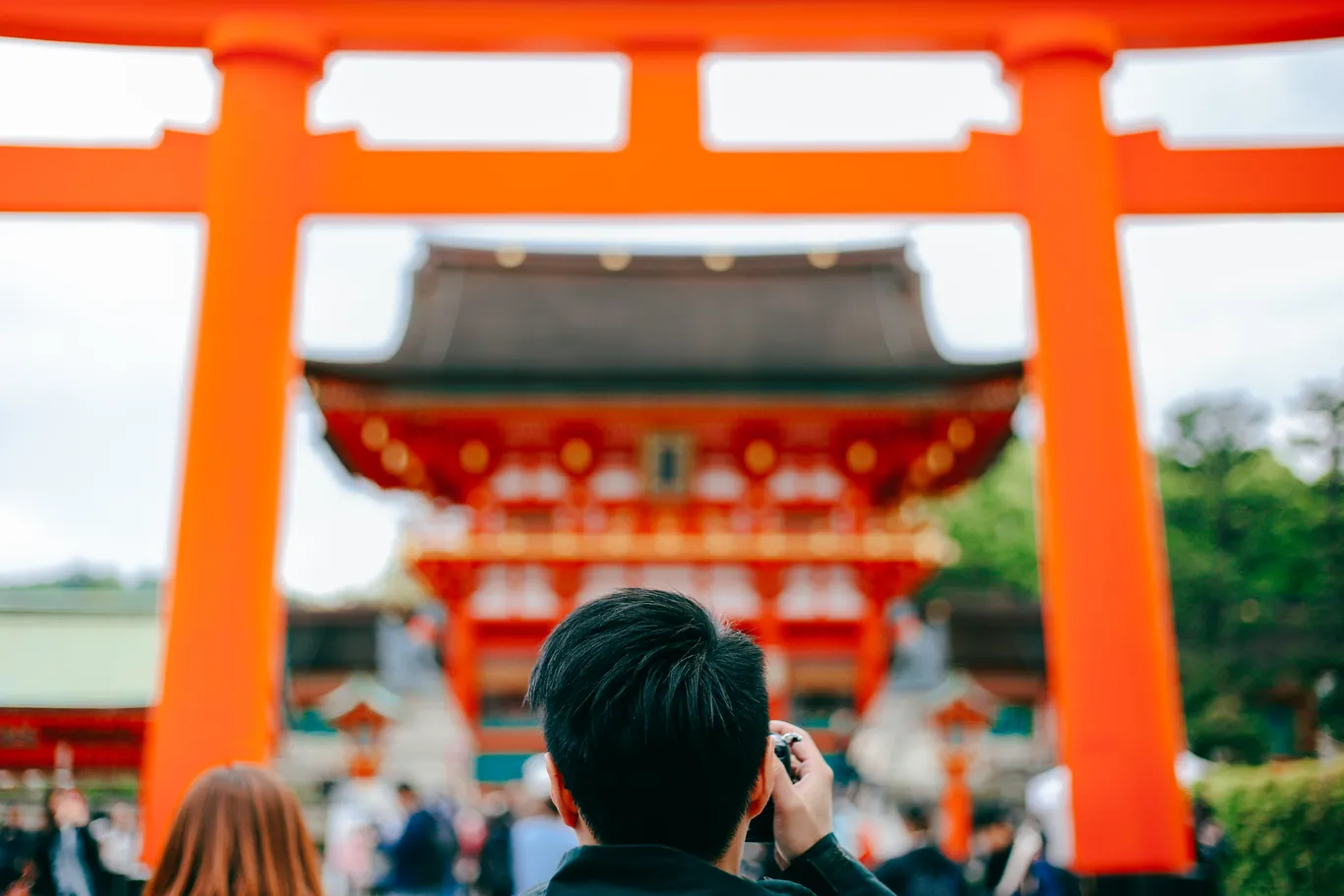 Besucher fotografieren das große orange Torii und das Tor des Fushimi Inari Taisha in Kyoto