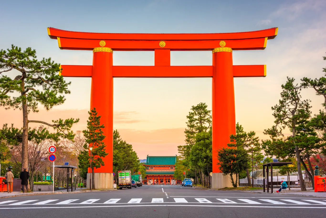 Das riesige rote Torii vor dem Heian-Schrein in Kyoto in der Abenddämmerung, davor eine breite Straße mit Zebrastreifen