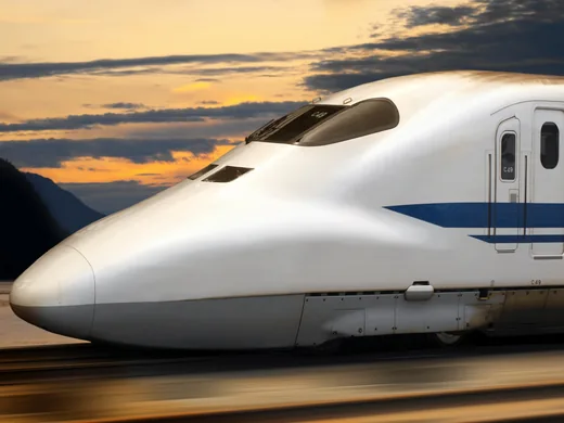 Shinkansen in der Abenddämmerung vor orange leuchtenden Wolken