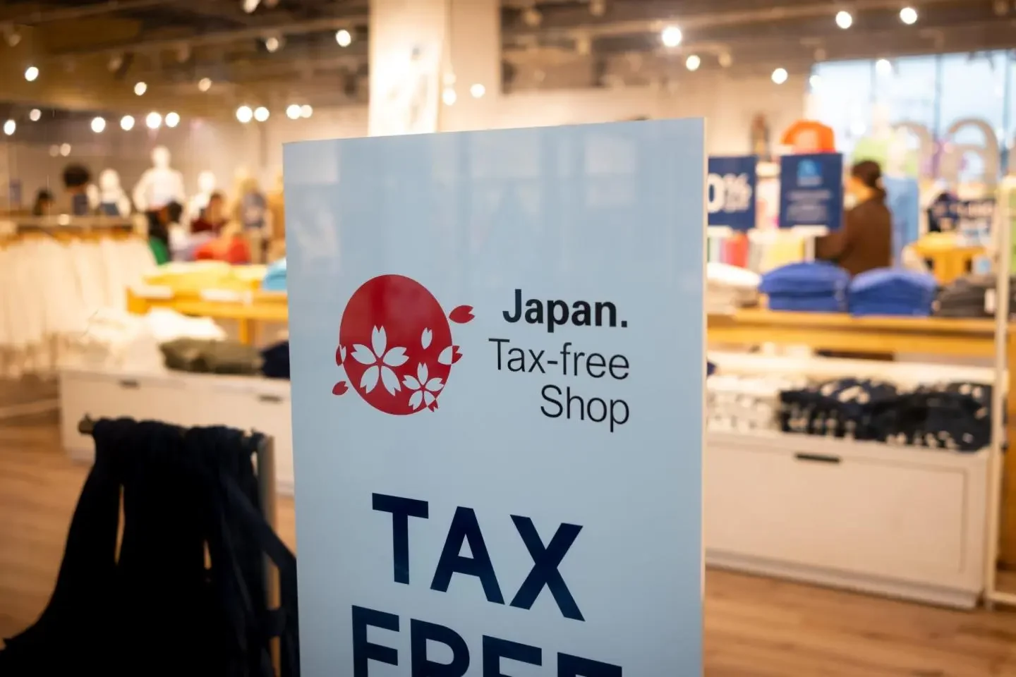 Aufsteller mit dem Zeichen Japan. Tax-free Shop und der Aufschrift TAX FREE in einem japanischen Bekleidungsgeschäft