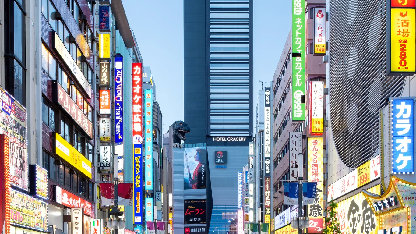 Straße in Kabukicho voller bunter Leuchtschilder, am Ende das Hotel Gracery mit dem Godzilla-Kopf