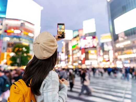 Eine Frau fotografiert die Leuchtreklamen an der Kreuzung von Shibuya